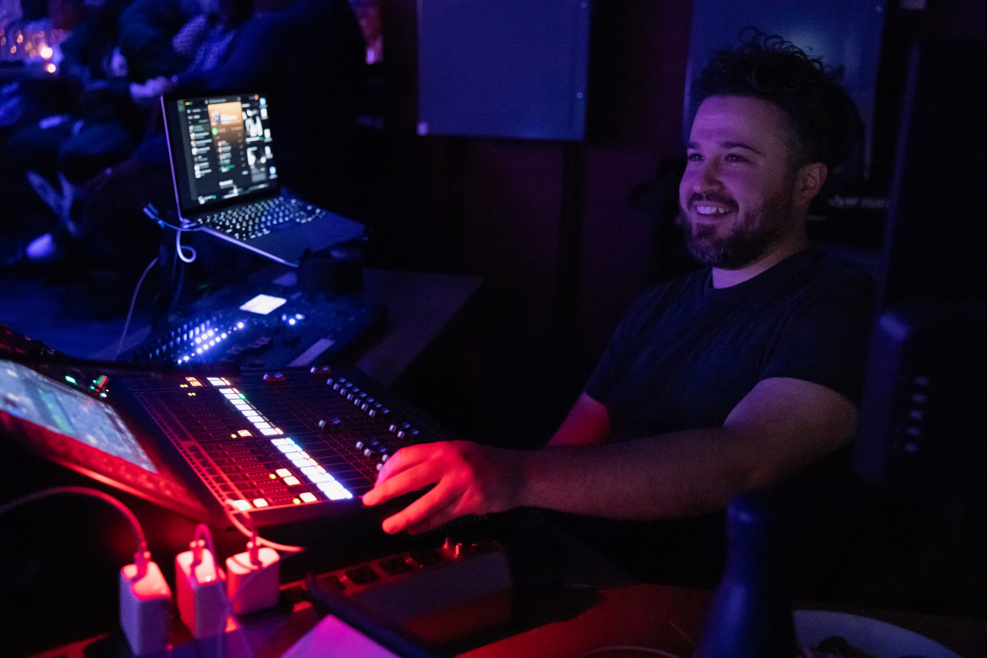 Sound engineer smiling at a lit-up mixing board